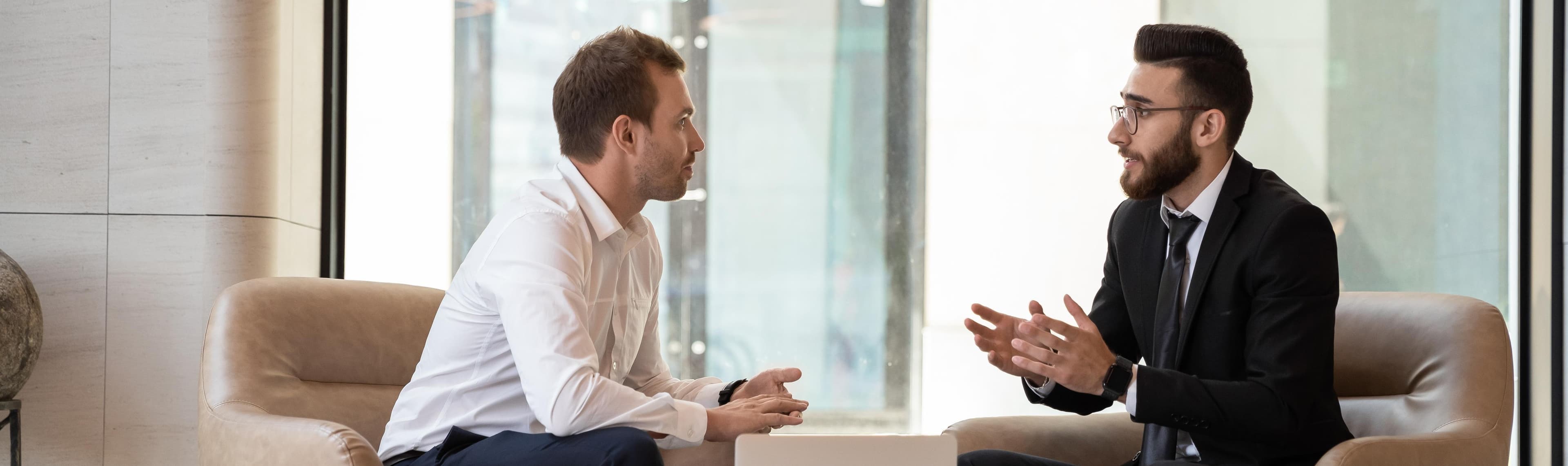 Two men gesture while discussing a challenge at work.  