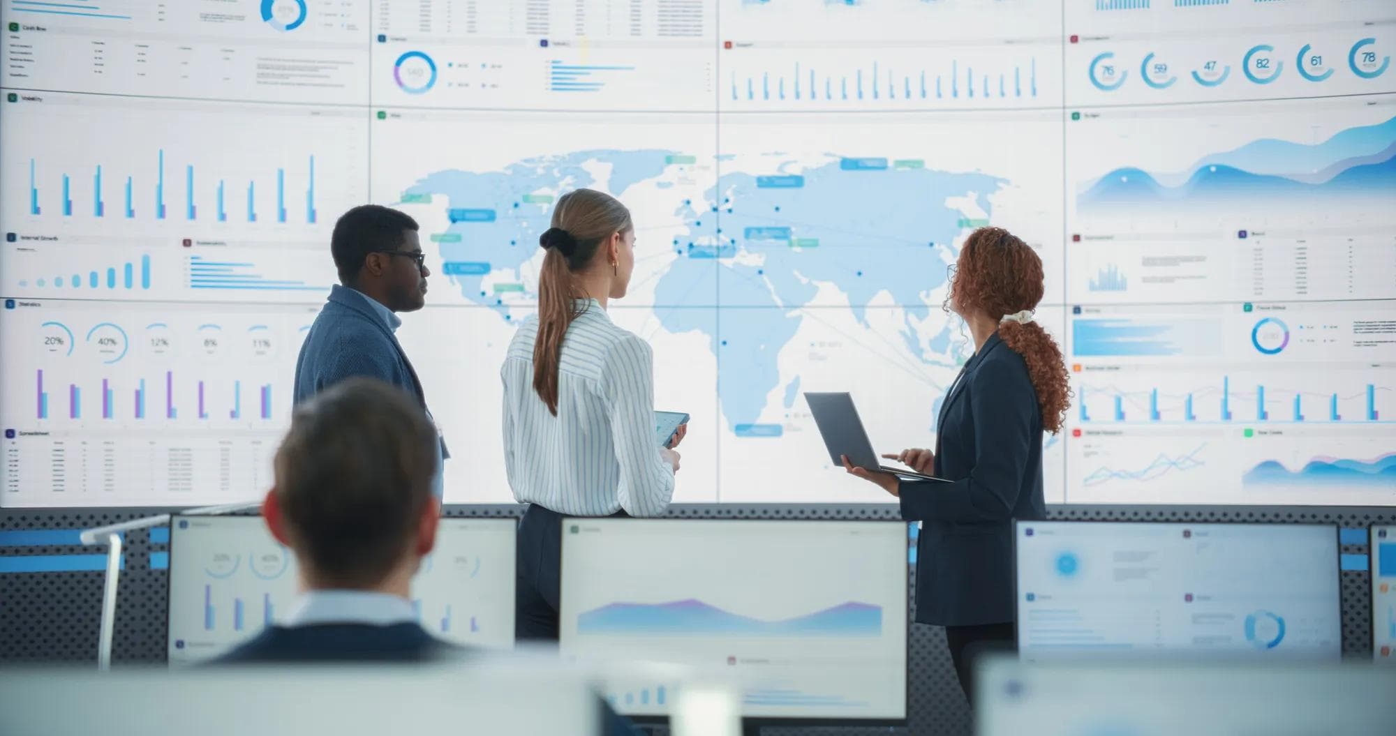 A diverse team discusses global risks in front of a digital map of the world.
