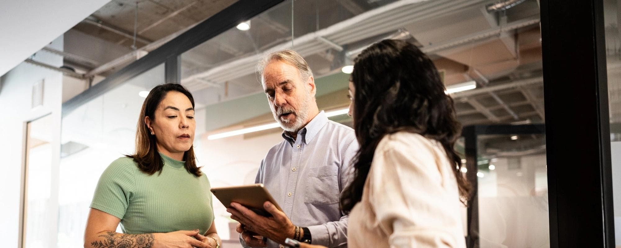 Coworkers of various ages discuss strategy in an office setting.