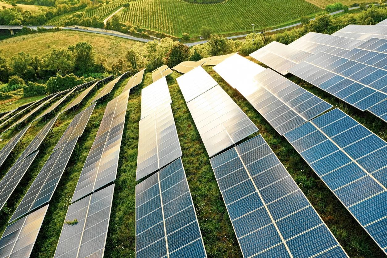 Solar panels on fields of green rolling hills.