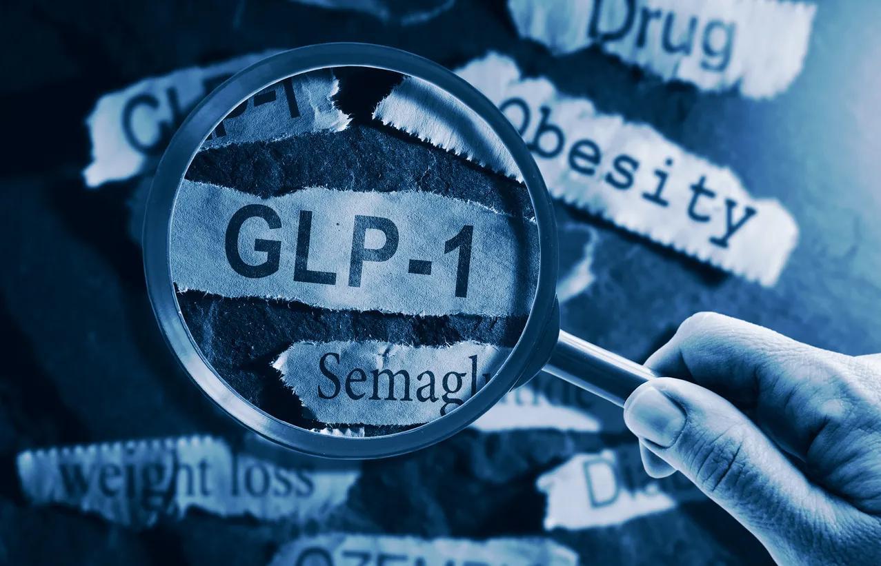 Magnifying glass on newspaper headlines “GLP-1”, “Drug”, “Weight Loss”, etc. 