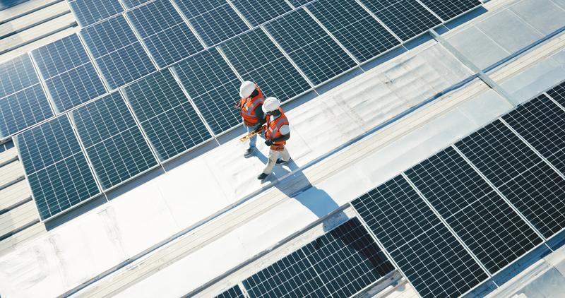 Team inspecting rooftop solar panels in urban setting