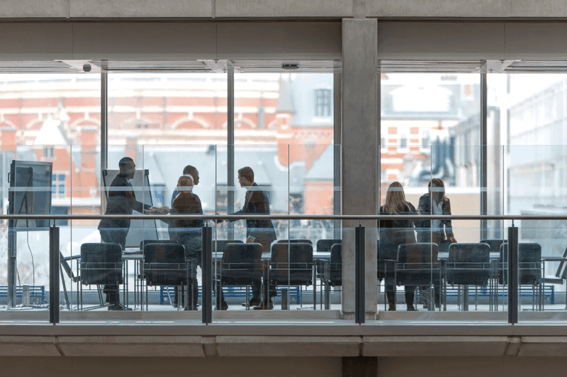 A group of six business people gather in a boardroom meeting.