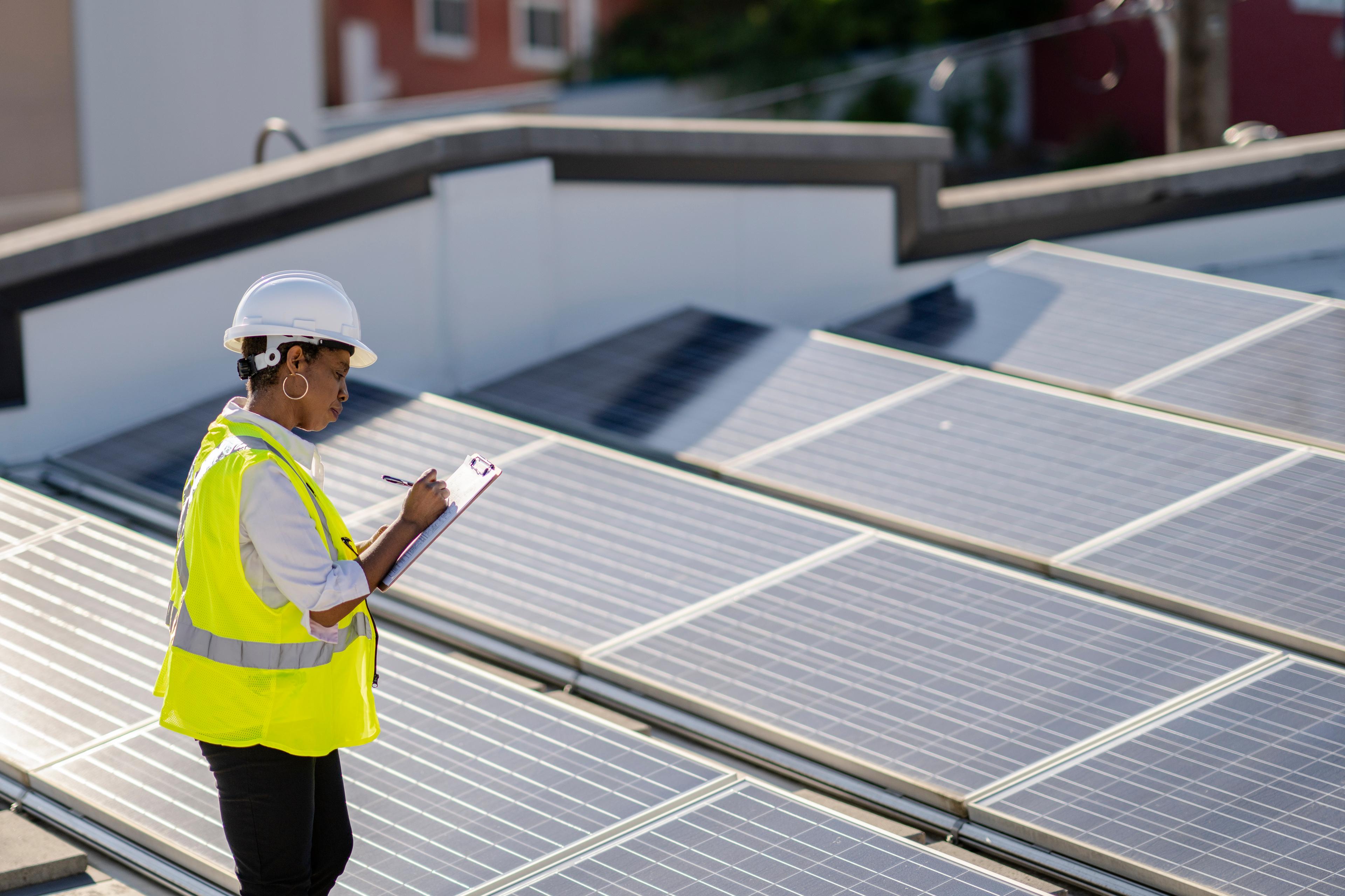 A woman monitors rooftop of solar panels to ensure efficiency and function.