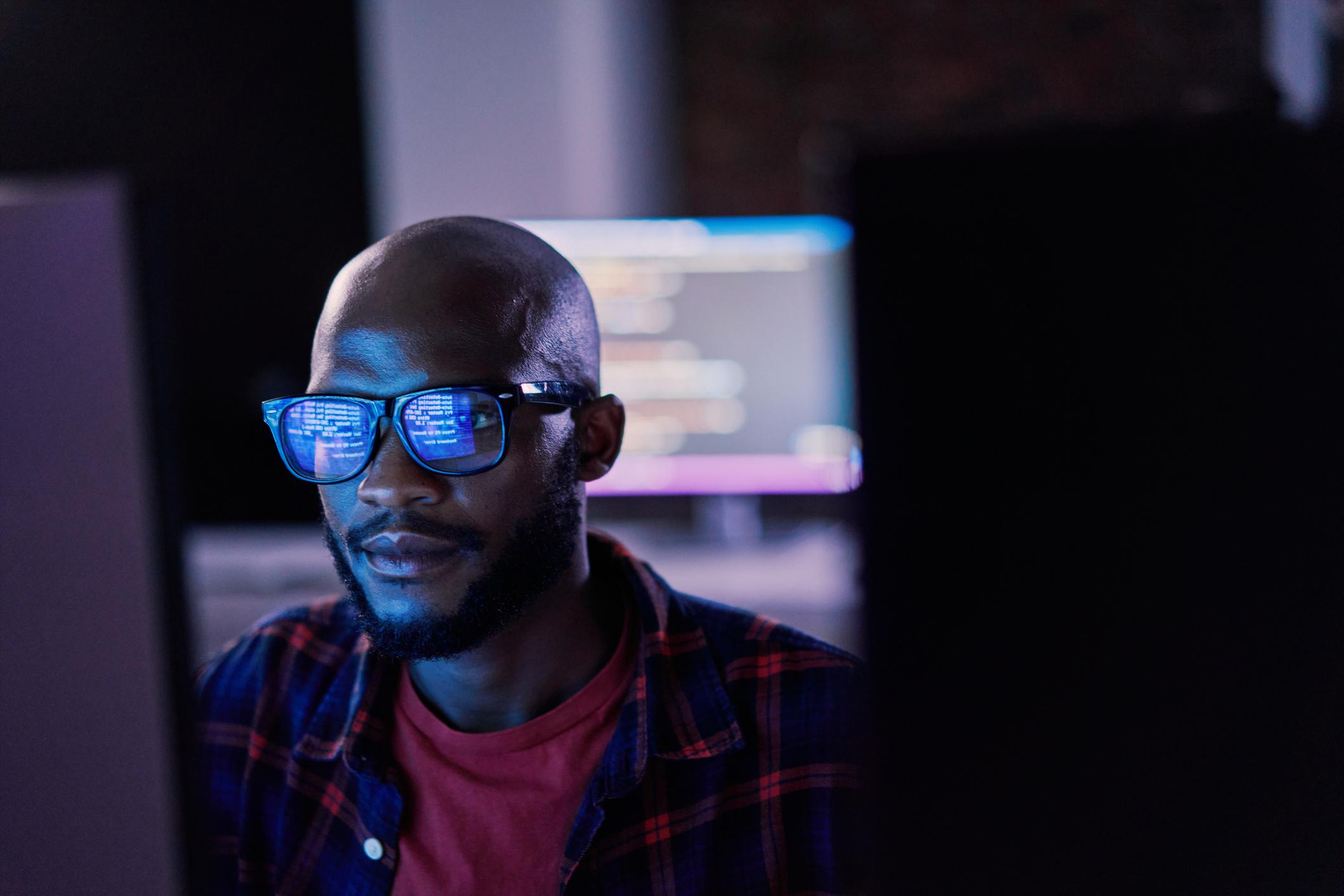 Man in front of computer screen with coding