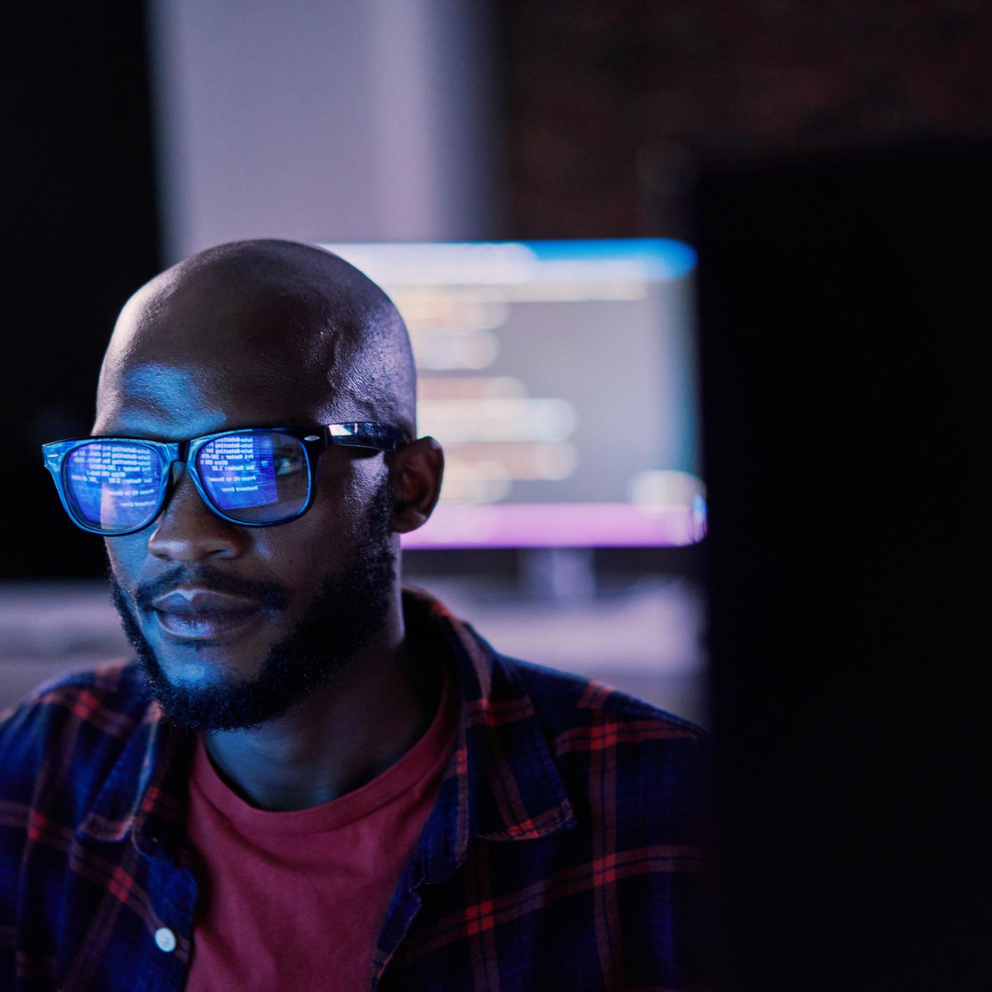 Man in front of computer screen with coding