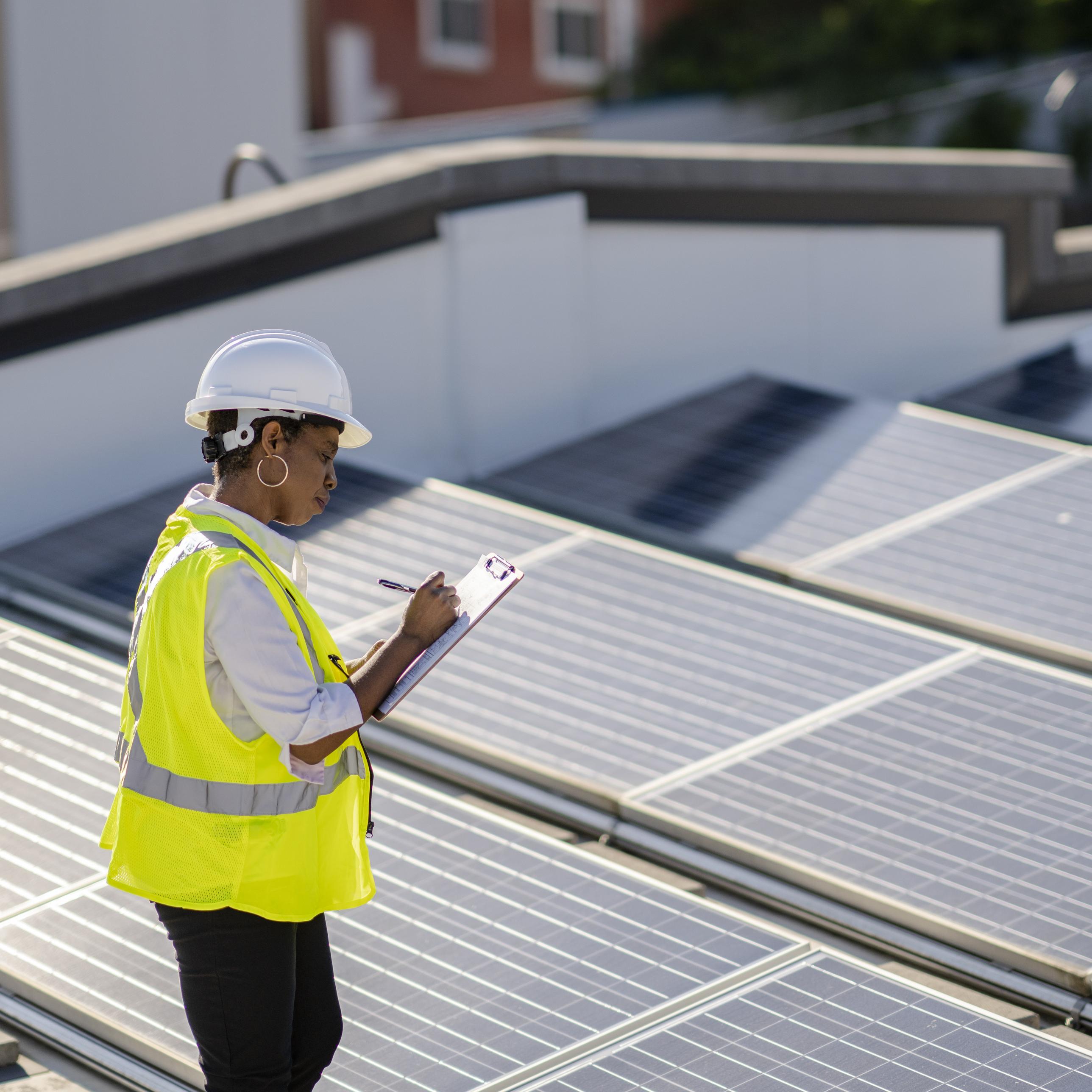 A woman monitors rooftop of solar panels to ensure efficiency and function.